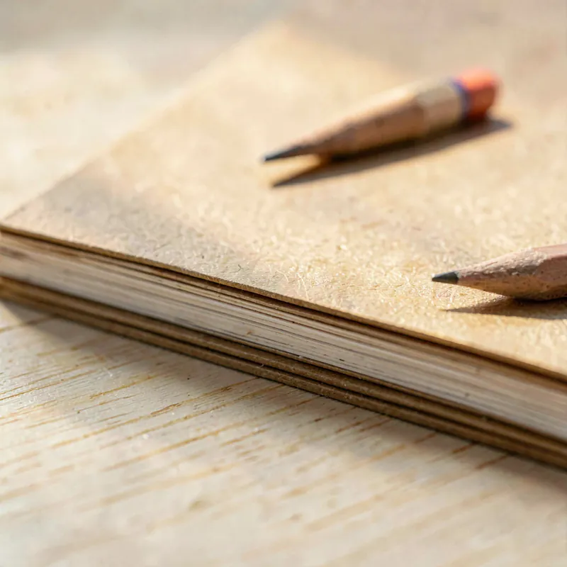 The edge of a stack of plain manila folders with a sharpened pencil laid across them