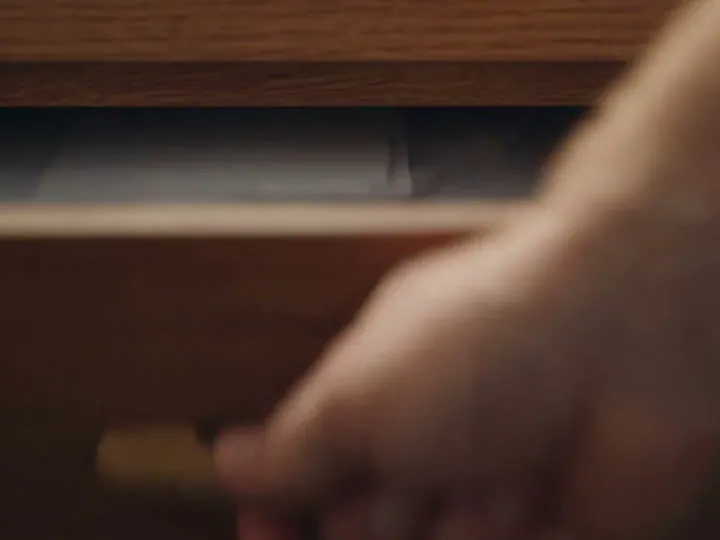 A hand opening a desk drawer full of loose paper slips